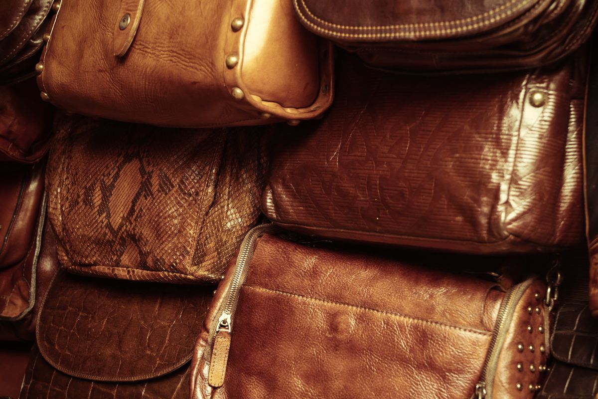 Hands inspecting the corner stitching of a used leather bag