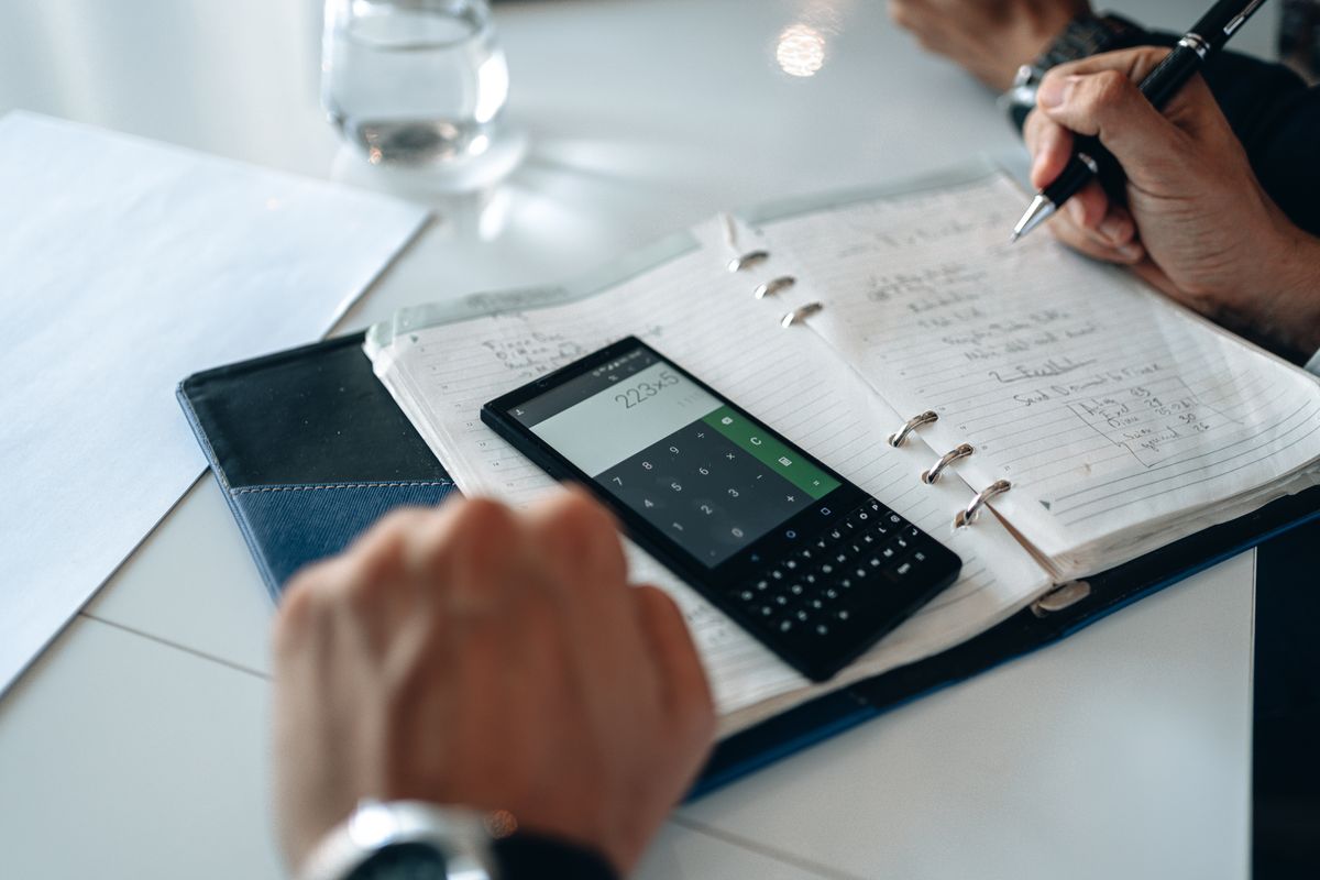 A worn leather wallet beside a calculator and a small notebook
