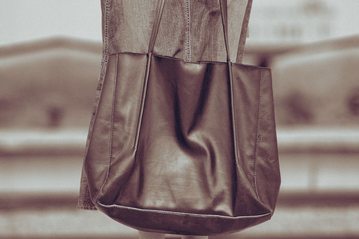 A structured work tote on an office desk beside a closed laptop